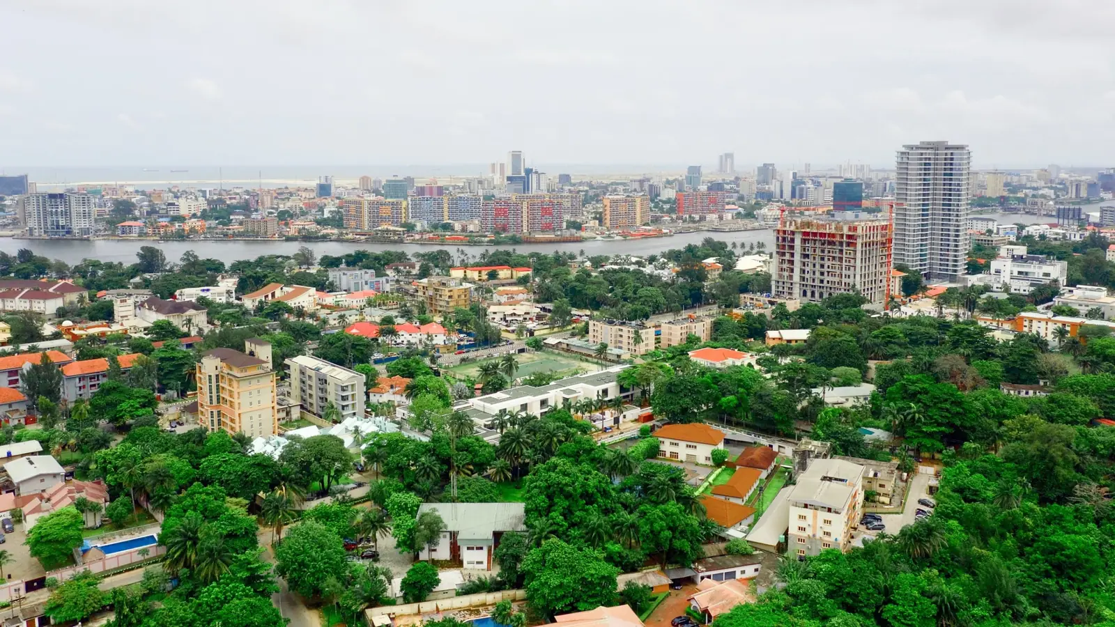 Low-rise housing and mature trees in Ikoyi with the Victoria Island skyline and lagoon behind