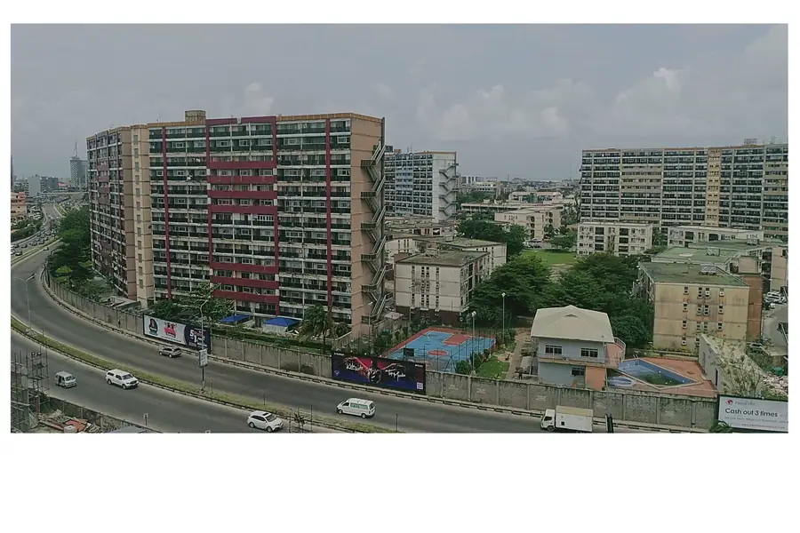 A mid-rise residential apartment block on a main road in Lagos with a service road and neighbouring blocks