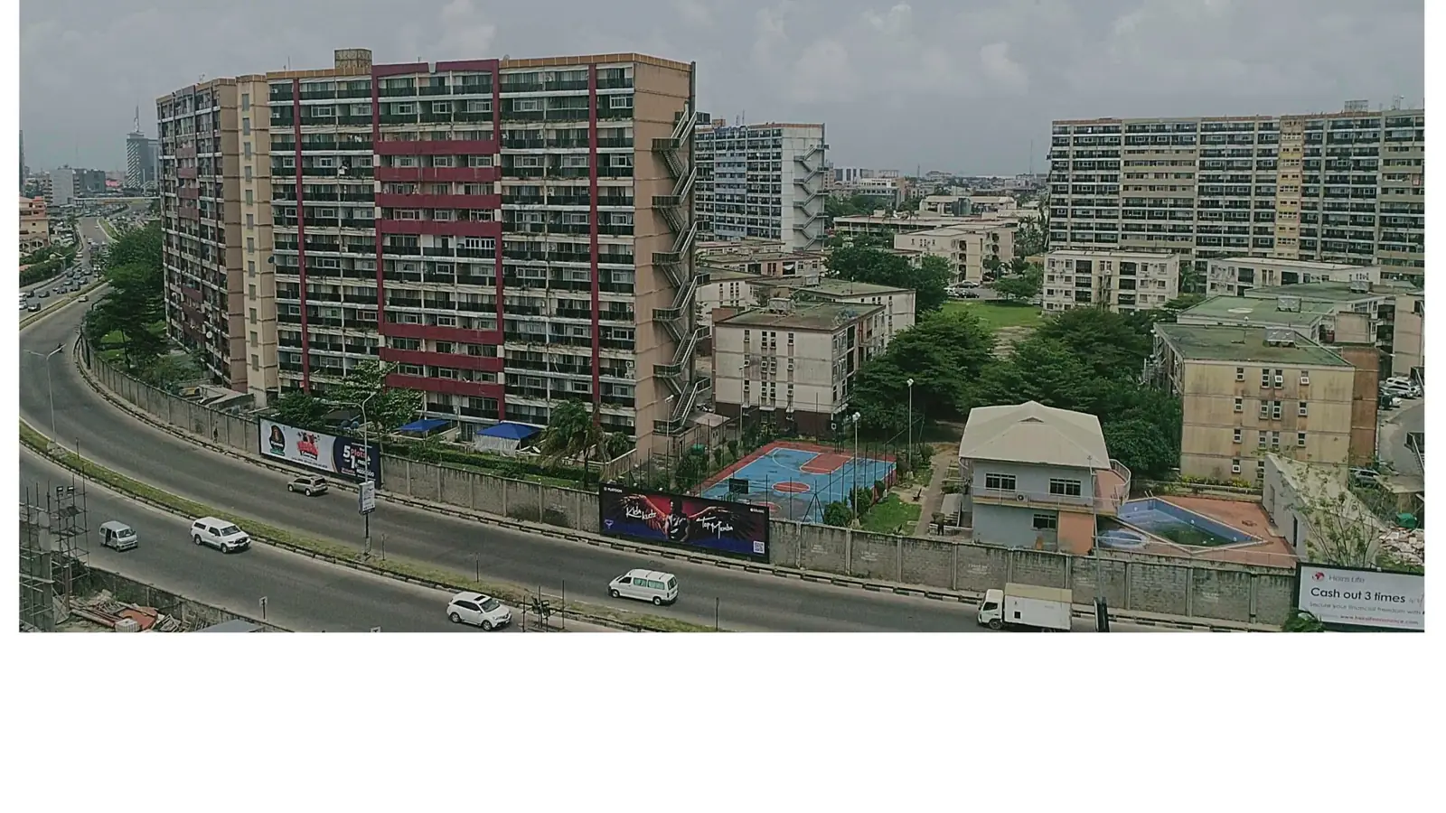 A mid-rise residential apartment block on a main road in Lagos with a service road and neighbouring blocks